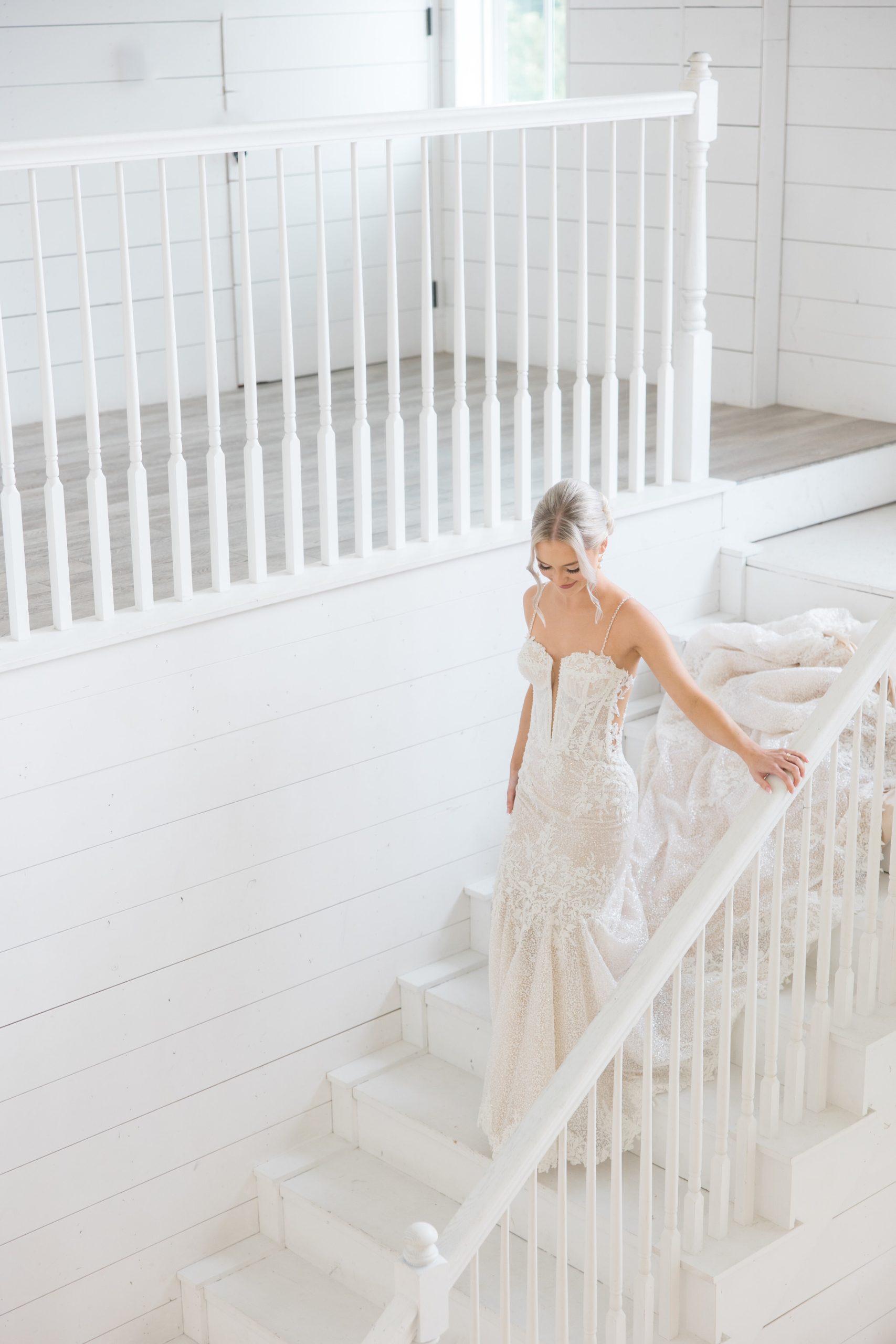 bride in gown walking down steps inside barn wedding venue